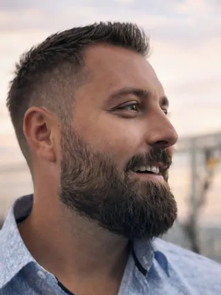 Mann med brunt skjegg og hår, med blå skjorte