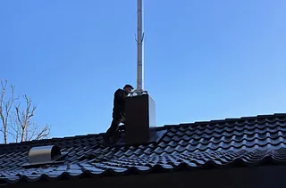 Mann inspiserer pipe på et tak